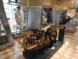 A cream-coloured wartime motorcycle among other museum items