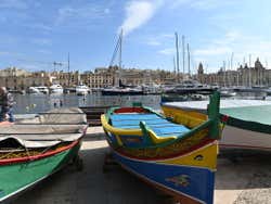 A row of colourful boats on the pavement next to the sea